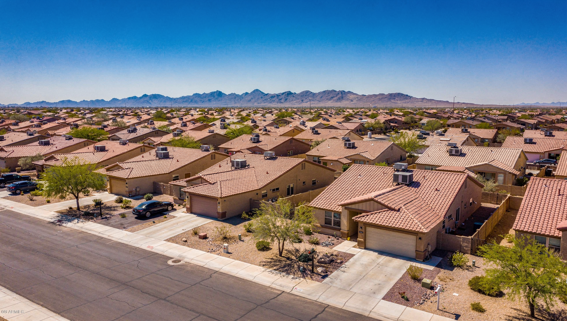Aerial view of a Phoenix valley neighborhood with rooftop AC units under a clear blue sky